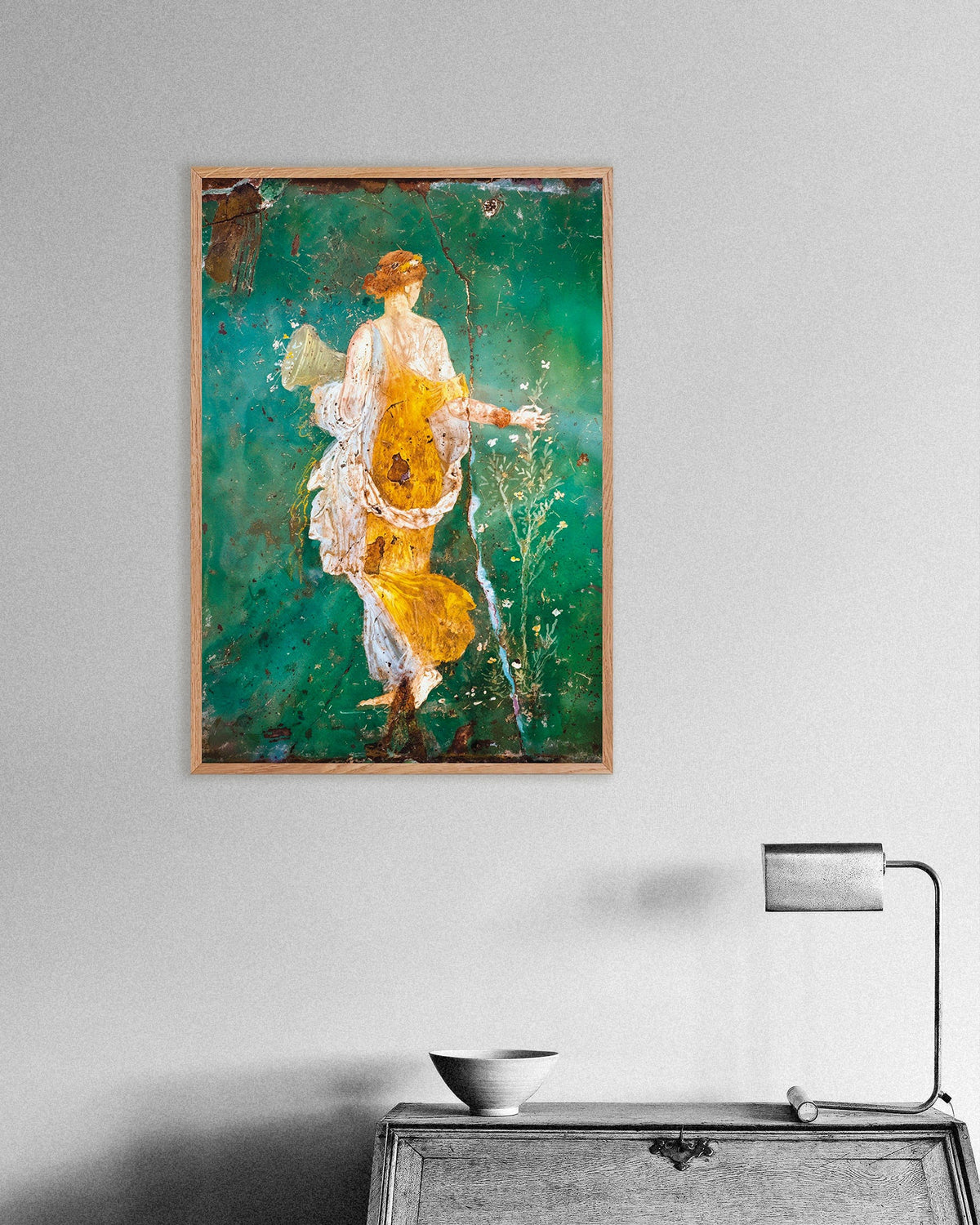 Oak-framed poster of the Flora fresco from Stabiae, a woman in a yellow robe on a green background, above an antique desk
