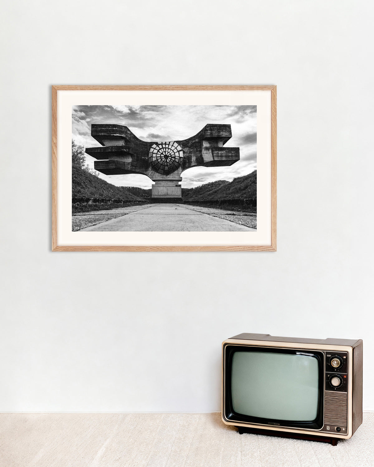 Plakat »Bevinget monument for enden af vejen« med ramme i naturtræ